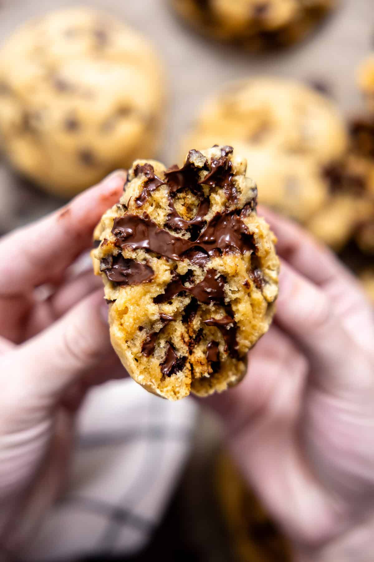 Thick chocolate chip cookie being split in half. 