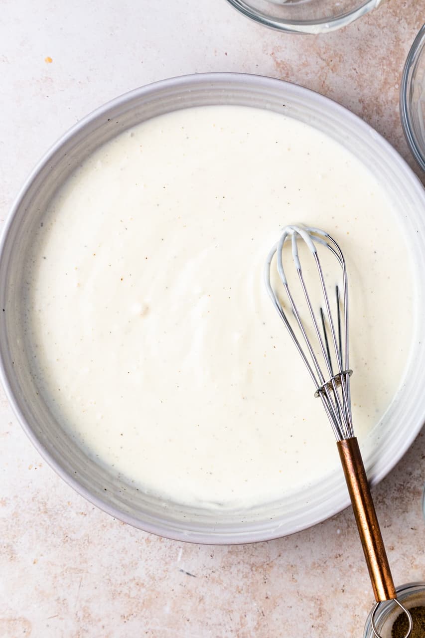 White bowl with whisked together homemade coleslaw dressing.