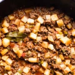 Skillet filled with homemade Mexican Picadillo, topped with a bay leaf.