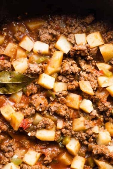 Skillet filled with homemade Mexican Picadillo, topped with a bay leaf.