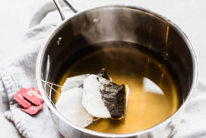 Saucepan filled with hot simple syrup with tea bags steeping.