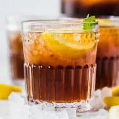 Glasses of sweet tea surrounded by ice and lemon wedges.