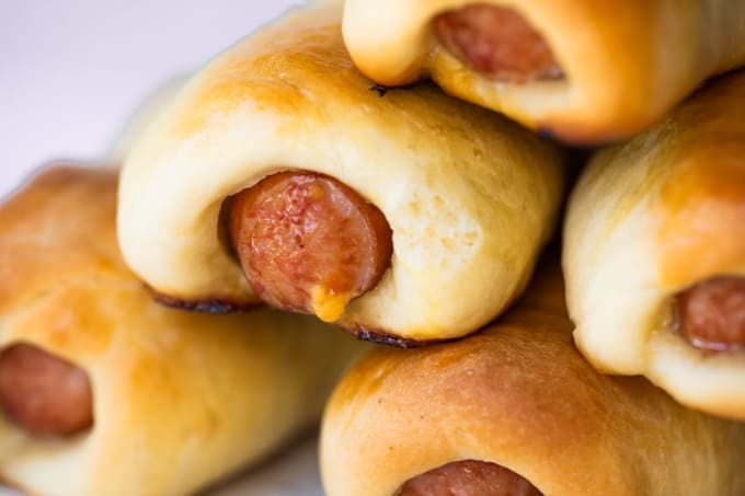 Stack of Texas Kolaches with cheese coming out of the sausage.
