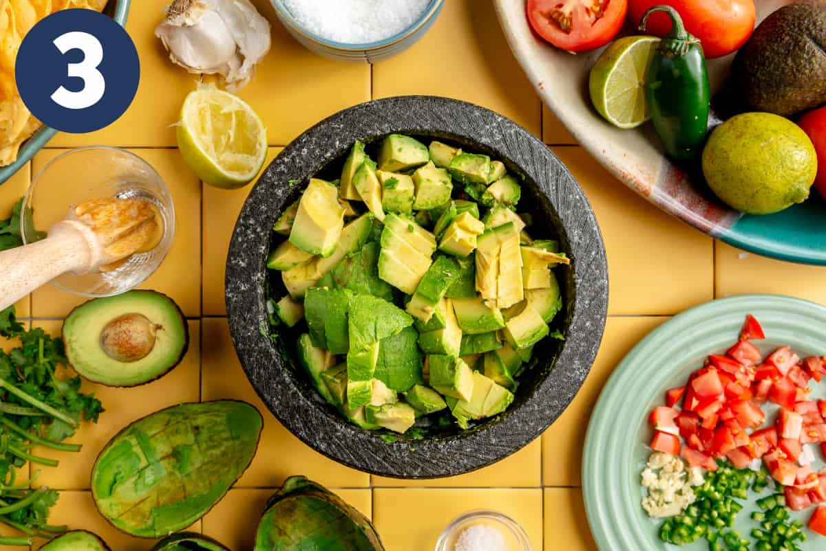 Chunks of avocado added to a molcajete.