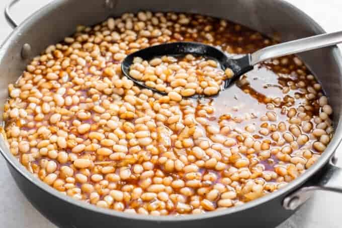 Beans stirred together with the flavored syrup to make baked beans.