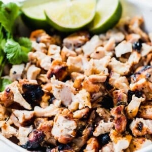 White bowl filled with diced grilled chicken to fill into soft white tortillas.