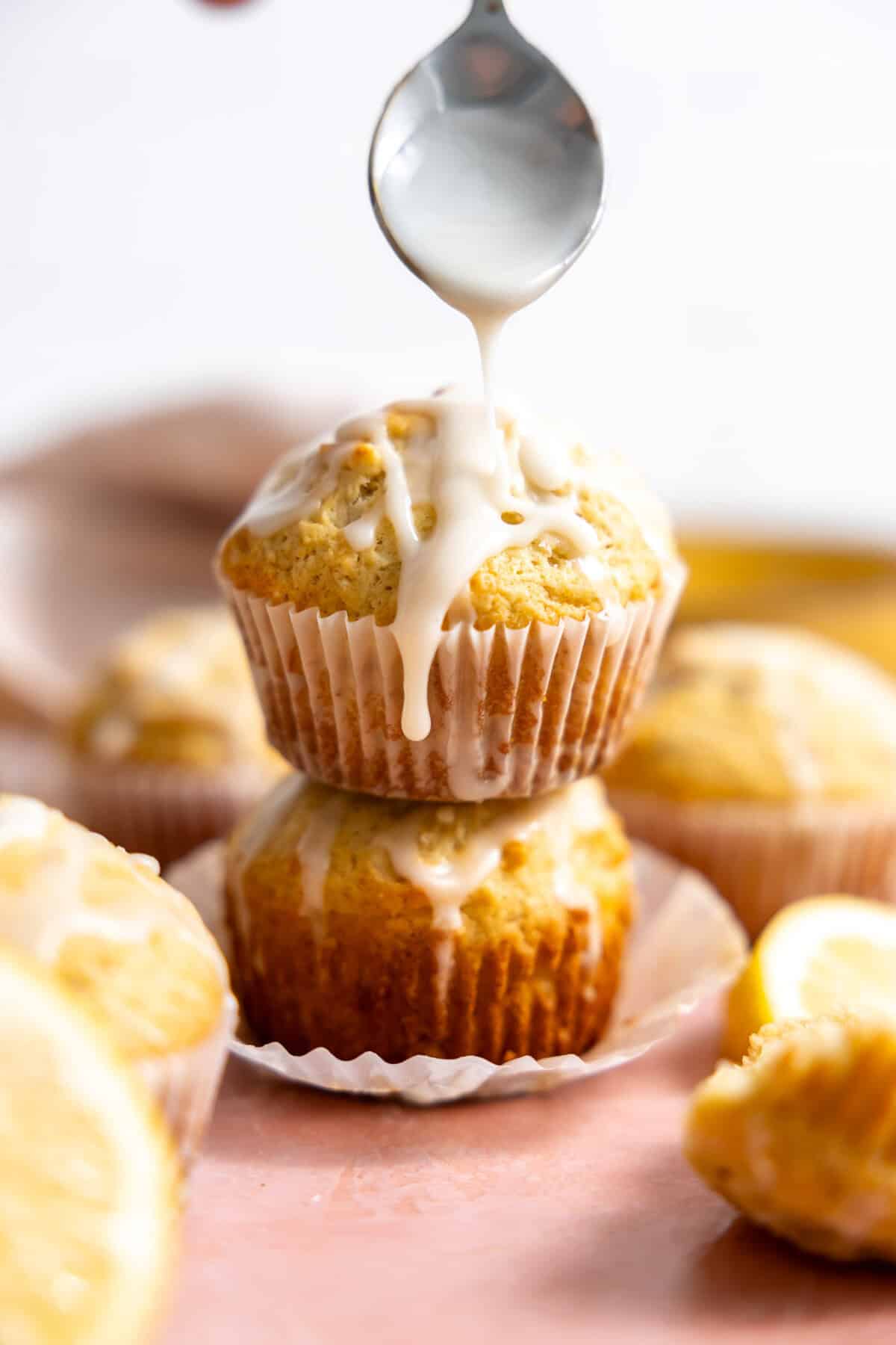 Lemon Muffins with graze being drizzled on top with a spoon.