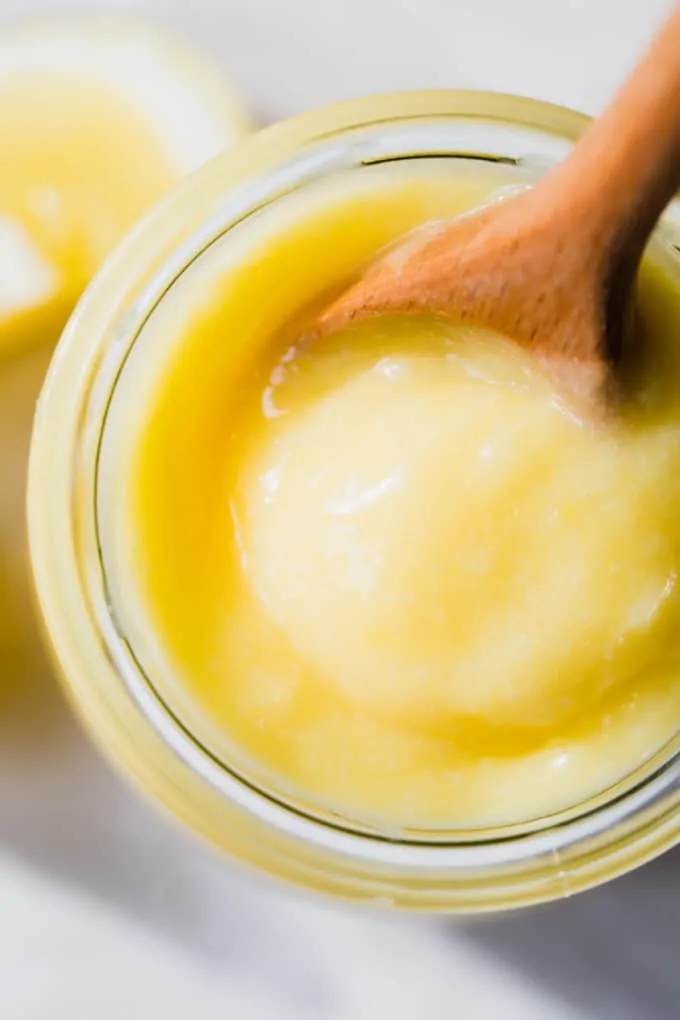 Overhead view of a glass jar filled with lemon curd, showing the smooth, creamy texture.