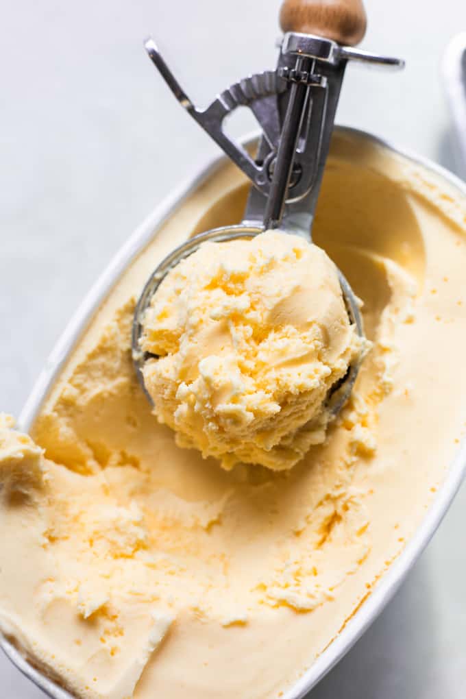 Scoop of ice cream being removed from a carton of vanilla ice cream.