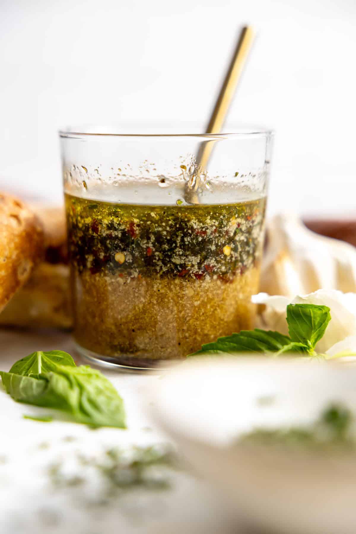 Glass filled with homemade Italian Dressing with a spoon to stir. 