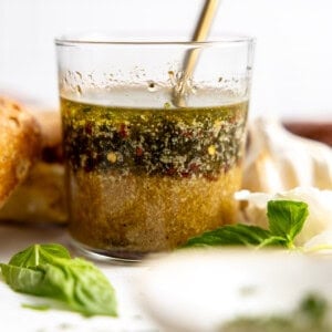 Glass filled with homemade Italian Dressing with a spoon to stir.