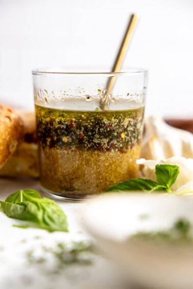 Glass filled with homemade Italian Dressing with a spoon to stir.