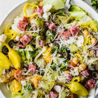 Italian chop salad, lettuce with diced salami, tomatoes, chick peas, tomatoes, red onion, and more all drizzled with Italian dressing, topped with whole pepperoncinis.