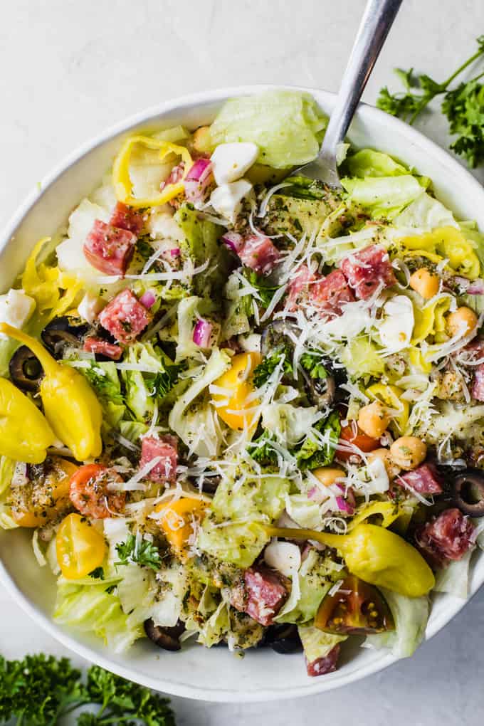 Italian chop salad, lettuce with diced salami, tomatoes, chick peas, tomatoes, red onion, and more all drizzled with Italian dressing, topped with whole pepperoncinis. 