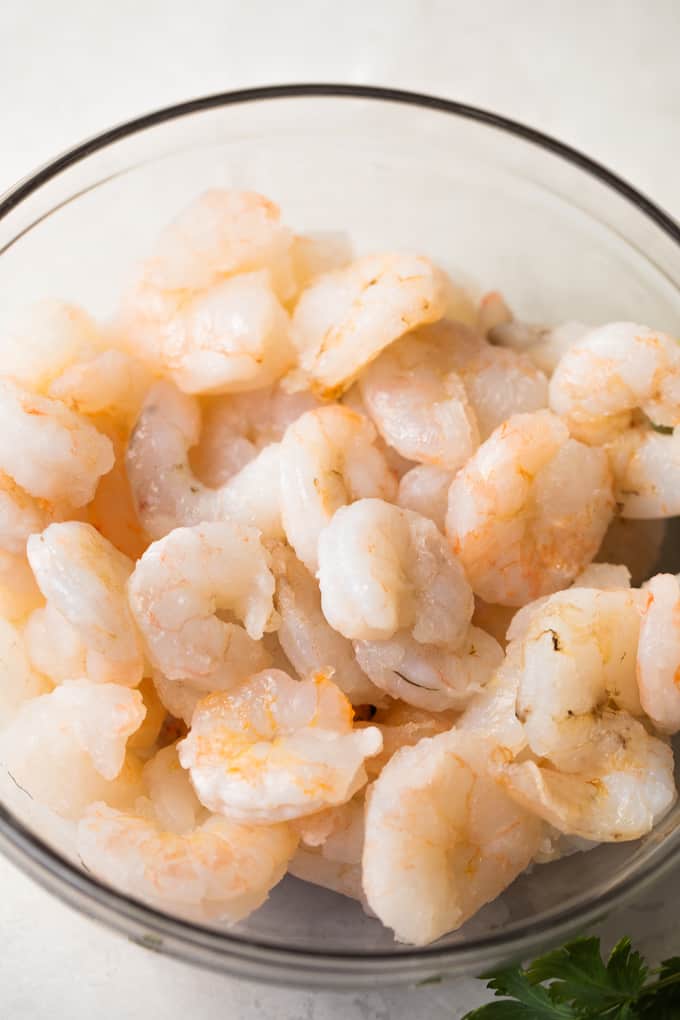 Raw shrimp in a small glass bowl.