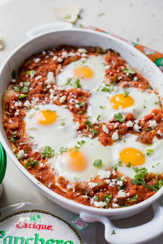 Huevos Rancheros breakfast casserole in a white casserole dish, topped with fresh diced cilantro. 