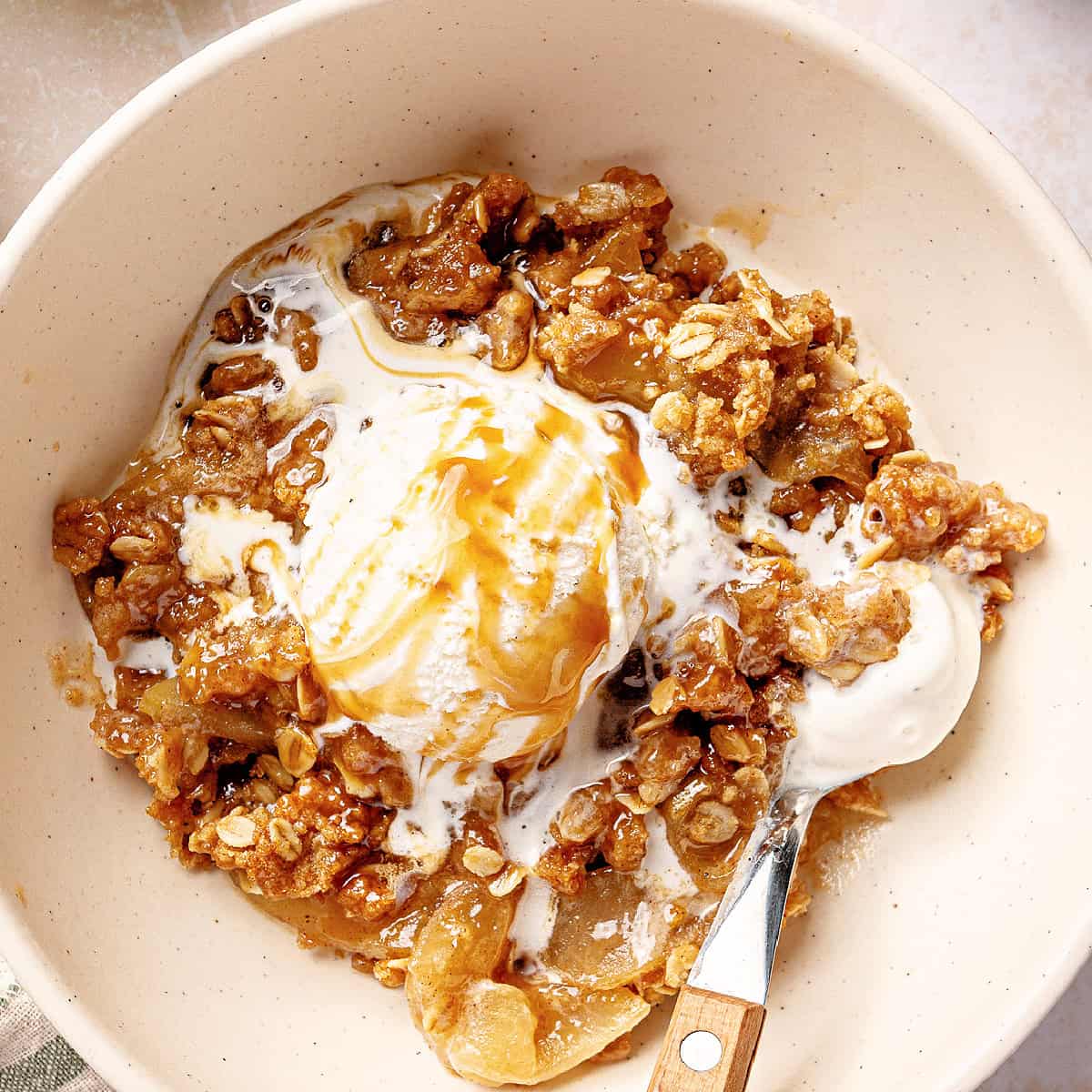 Caramel apple crisp served with ice cream in a bowl.