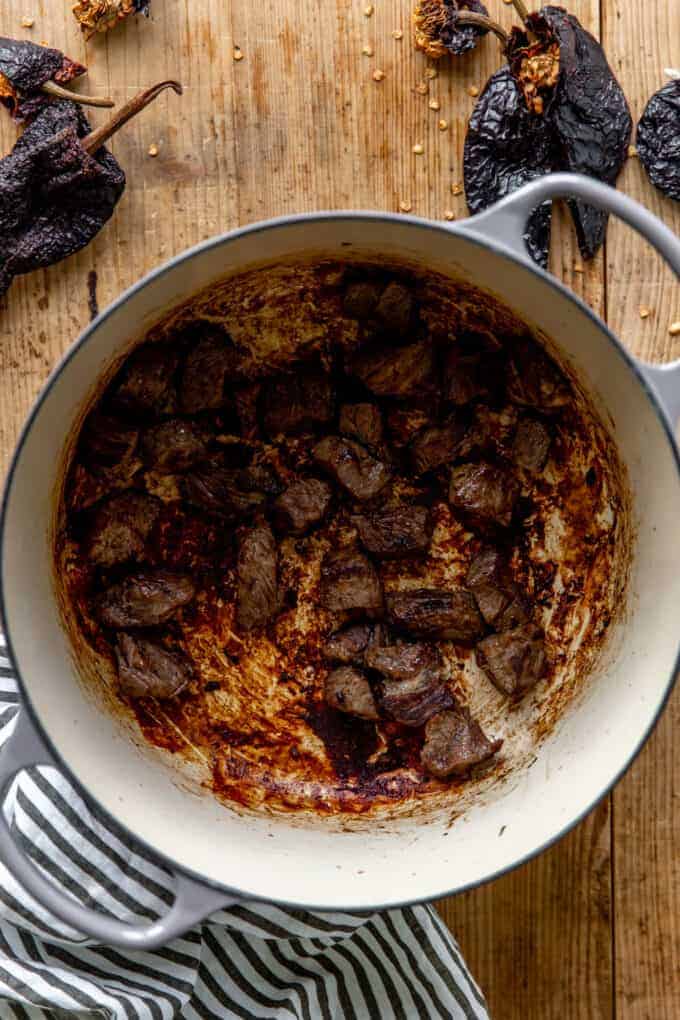 Chuck roast wird in einem großen holländischen Ofen sautéed, um Chili mit zu machen.