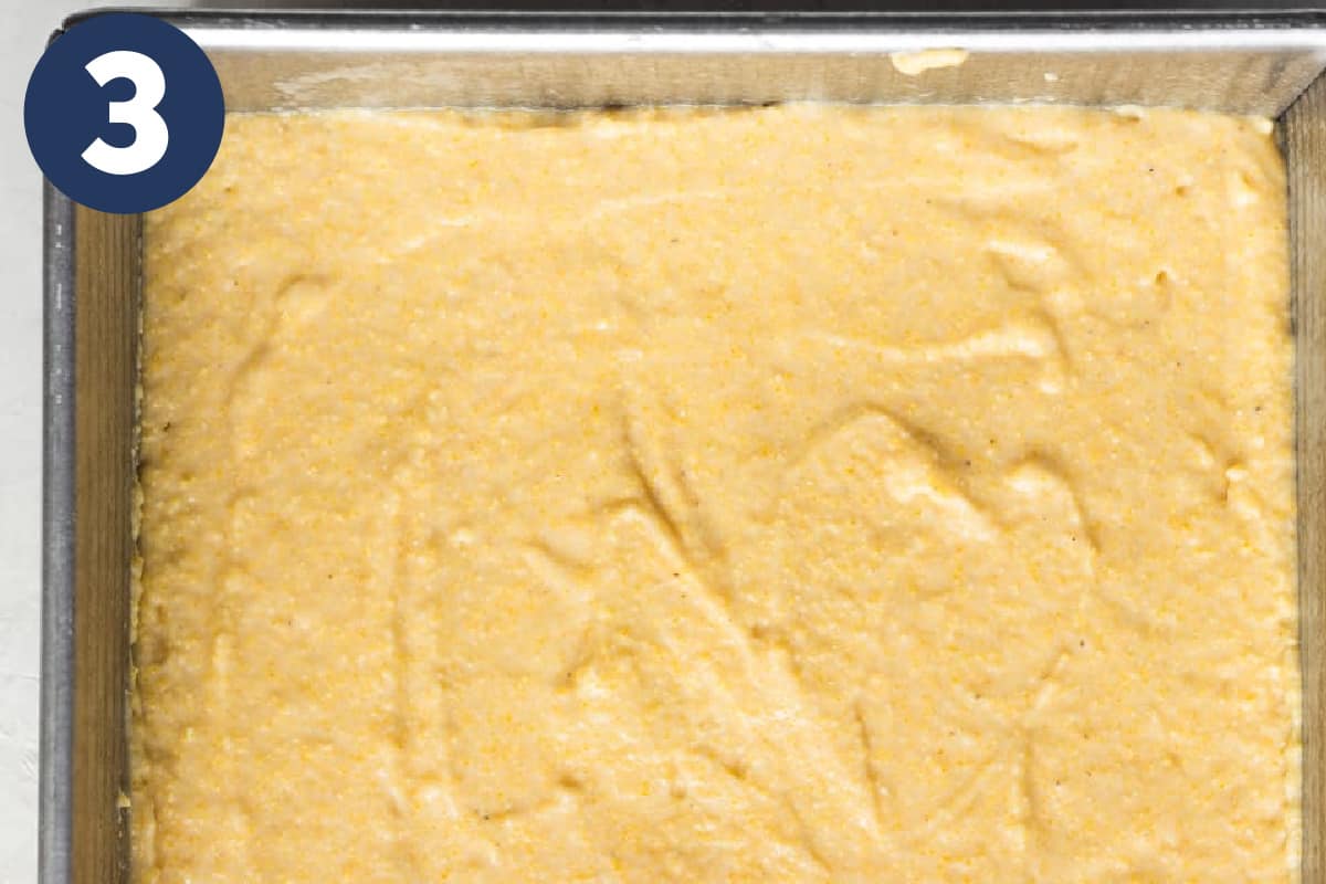 Buttermilk cornbread batter spread out evenly in a square baking pan.