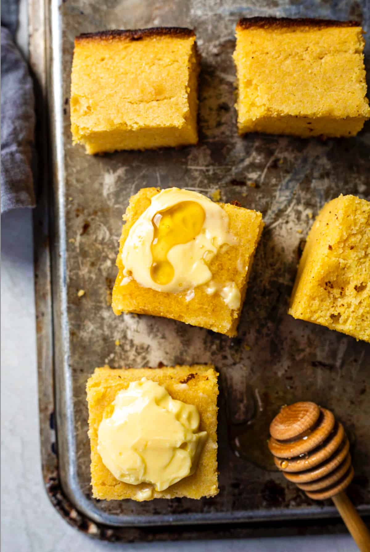 Overhead image of cornbread slices with butter and honey on top. 