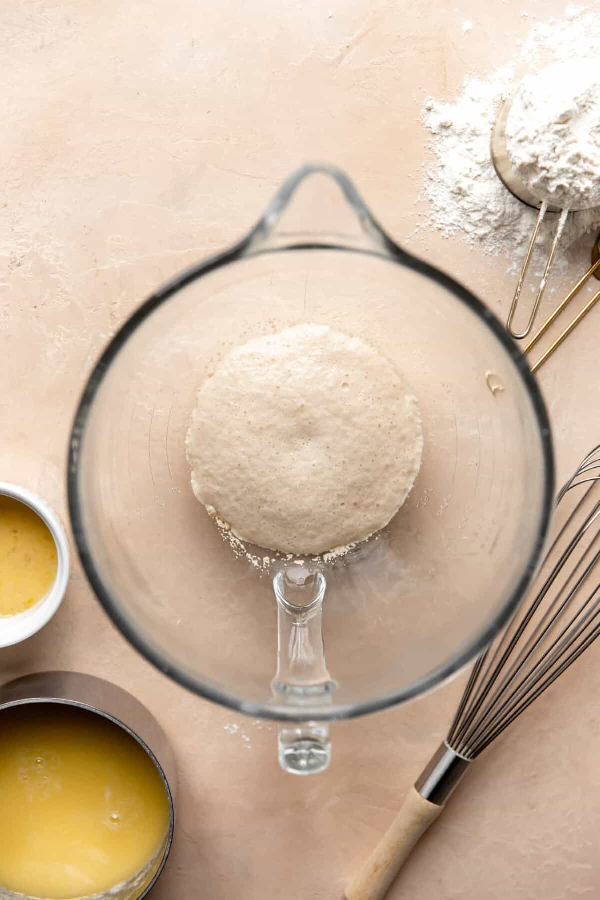 Ingredients in a stand mixer bowl to make bread rolls.