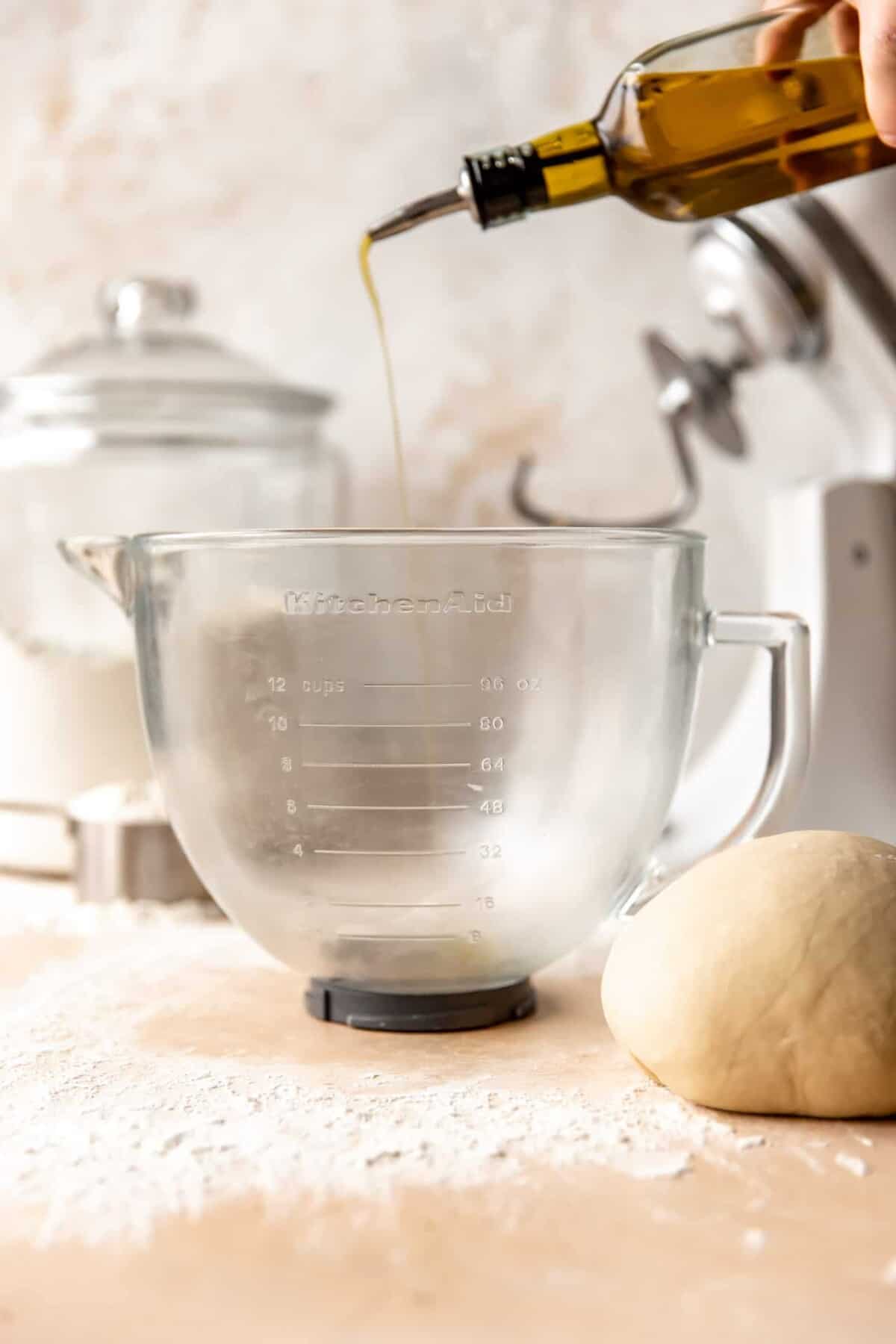 Oil drizzling into a glass bowl before adding dough in to rise.