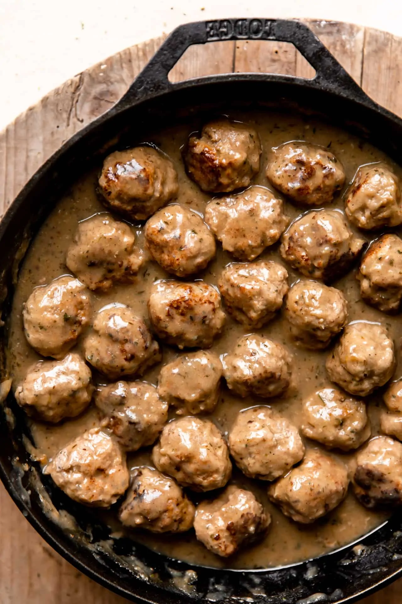 Cooked turkey meatballs in a large cast iron skillet simmering in creamy gravy.