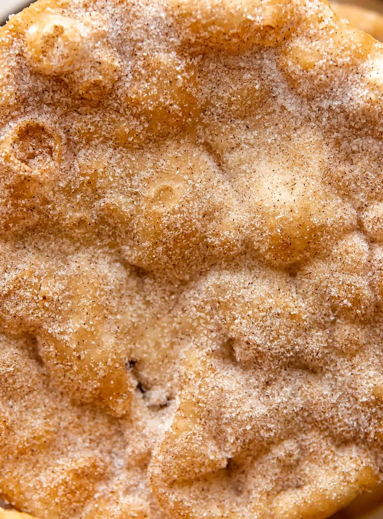 Up close view of bunuelos fried and coated with cinnamon sugar.