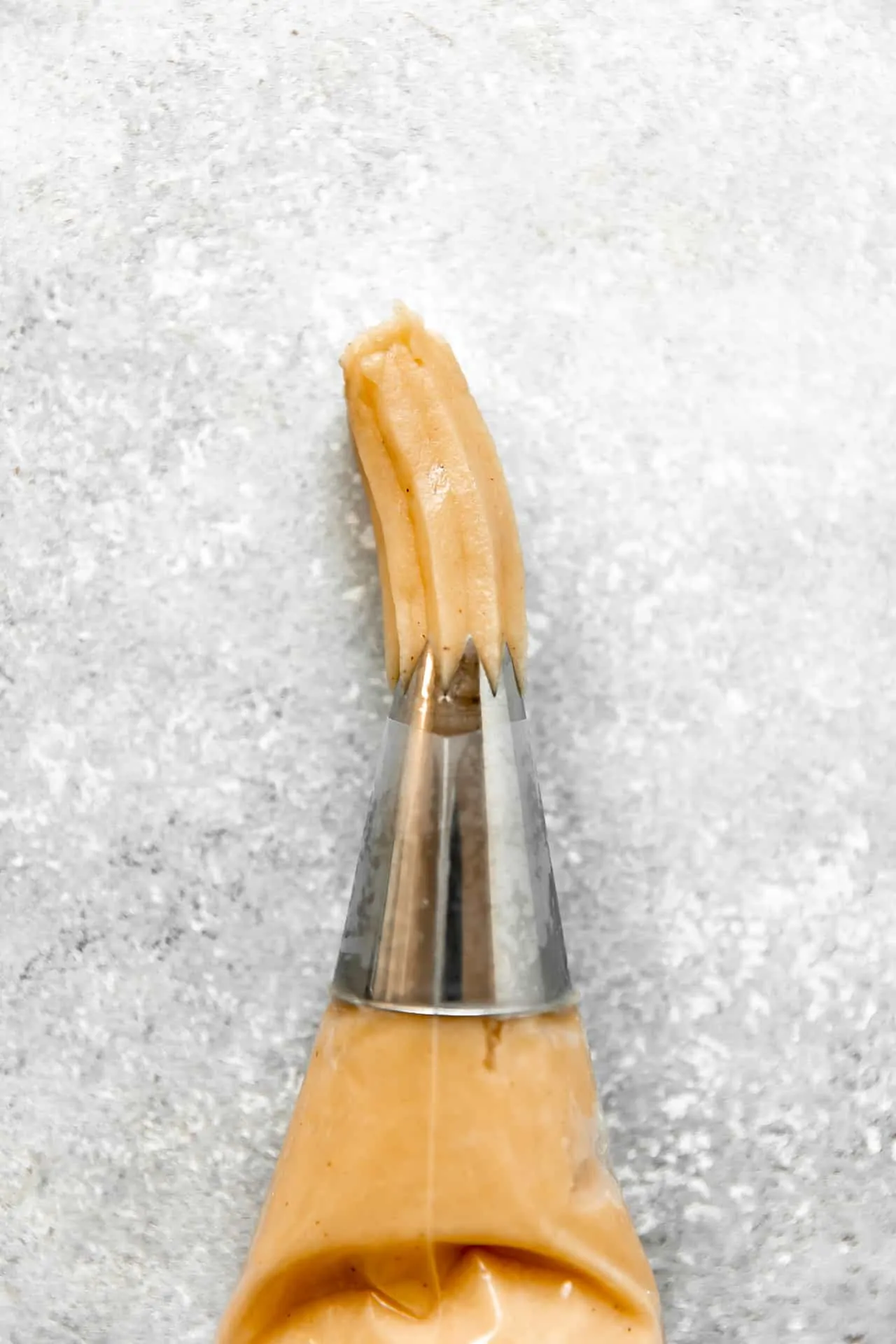 Dough being squeezed through a star tip on a pastry bag.