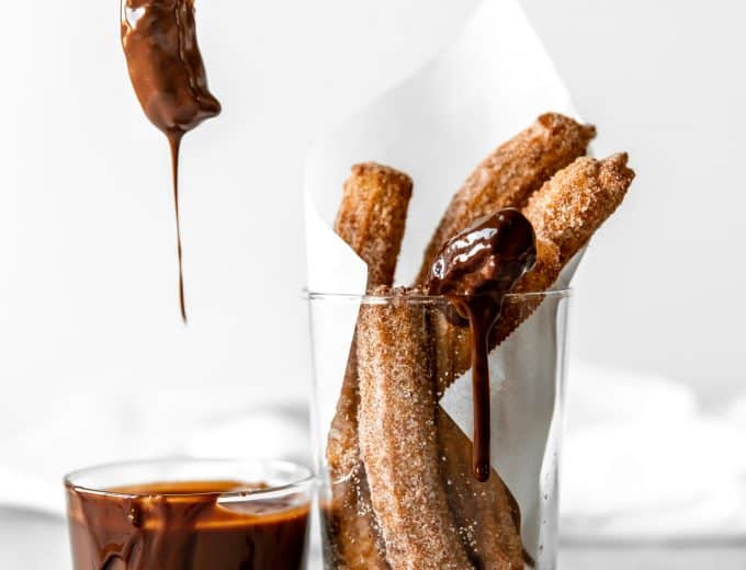 Churro being dipped into chocolate fudge.
