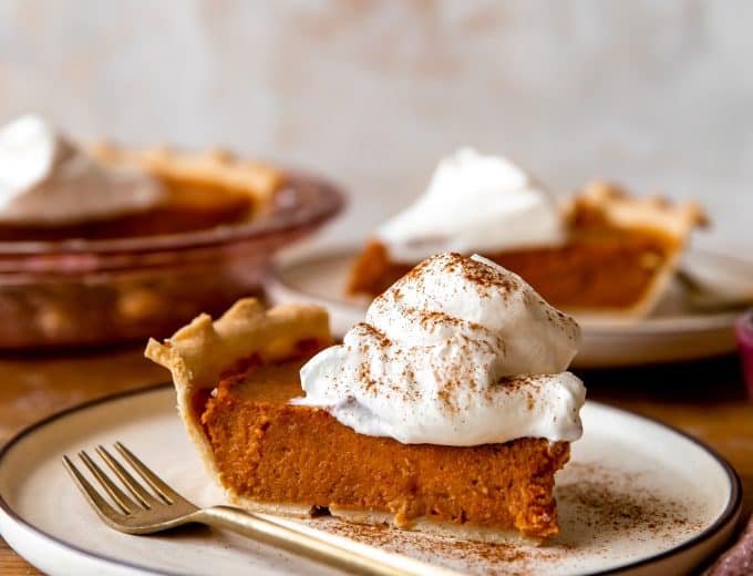 Slice of sweet potato pie with a swirl of whipped cream on top.