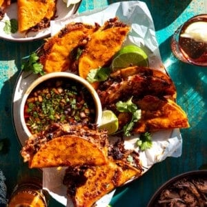 Plate filled with birria tacos and a bowl of consommé.