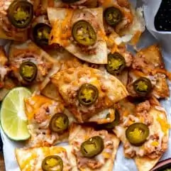 Texas Nachos served with some lime wedges and guacamole.