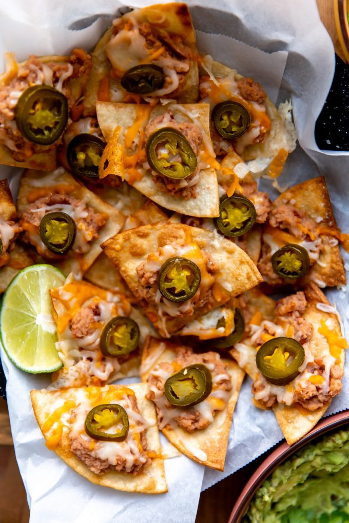 Texas Nachos serviert mit Limettenschnitzen und Guacamole.