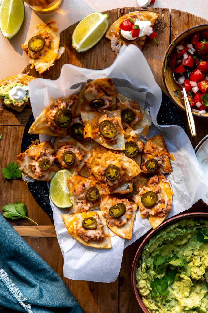Tray of texas style nachos served with guacamole and salsa on the side.