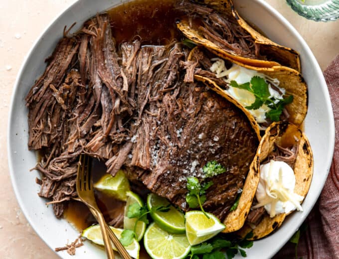 Bowl filled with shredded Mexican brisket and corn tortillas for making tacos.