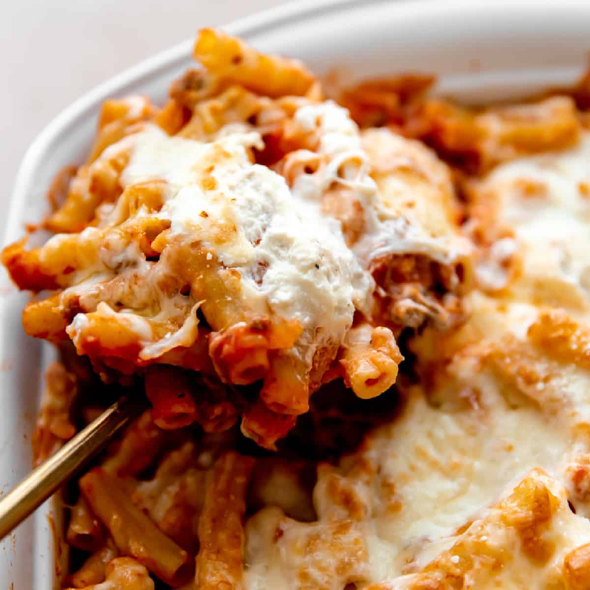 Baked ziti being served on a spoon. 