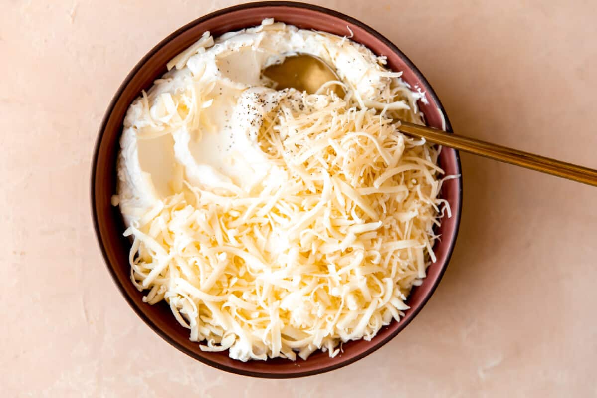 Ricotta being mixed with grated cheese and seasonings. 
