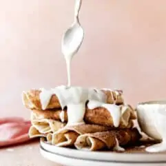 Stack of cinnamon tortillas being drizzled with cream cheese glaze.
