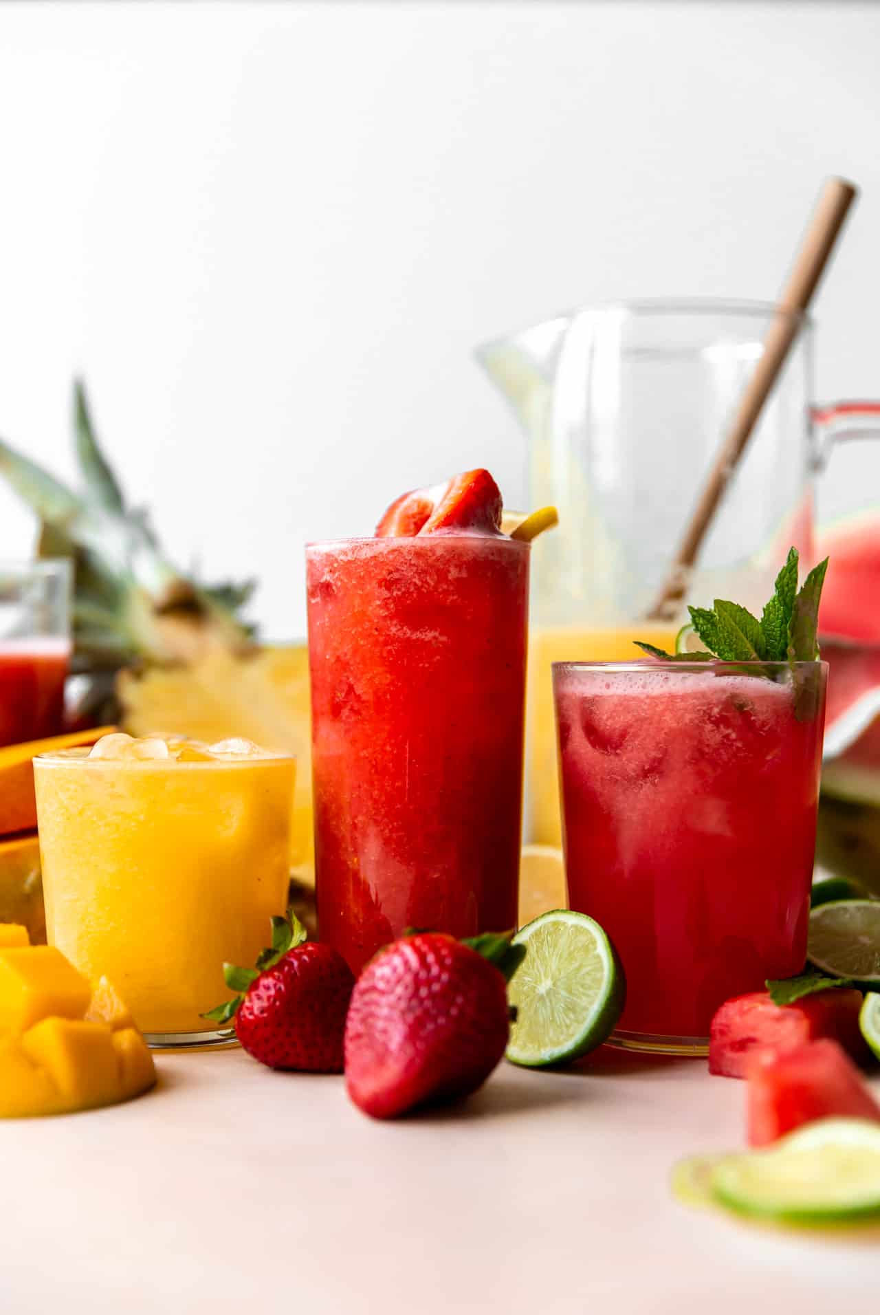Glasses of agua fresca lined up showing strawberry, watermelon and a pineapple mango.