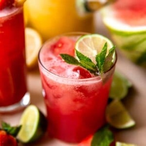 Glass of watermelon agua fresca garnished with mint and lime.