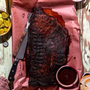 Whole brisket laying on peach paper after being smoked.
