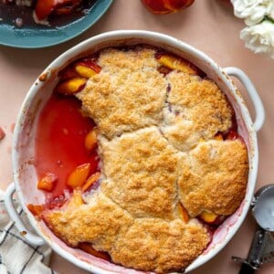 Baked peach cobbler in a round dish.