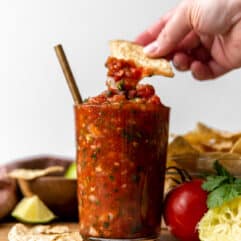 Jar of salsa with a chip being dipped in.