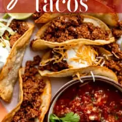 Ground beef tacos on a plate served with a bowl of salsa.