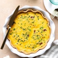 Baked Quiche in a white pie dish with a knife laid on top for serving.