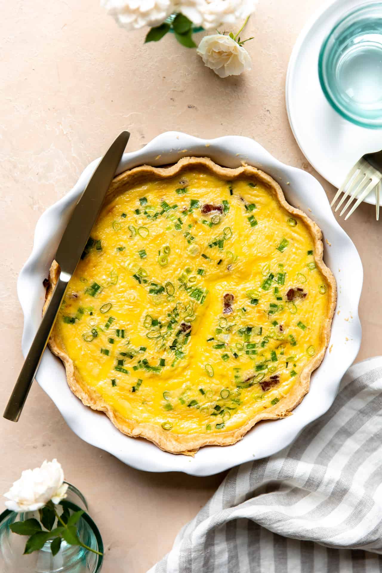 Baked Quiche in a white pie dish with a knife laid on top for serving. 