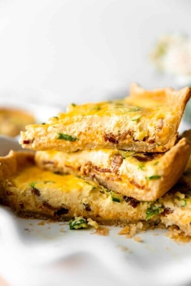 Sliced quiche stacked in a pie dish showing a custard egg filling and flakey pie crust.