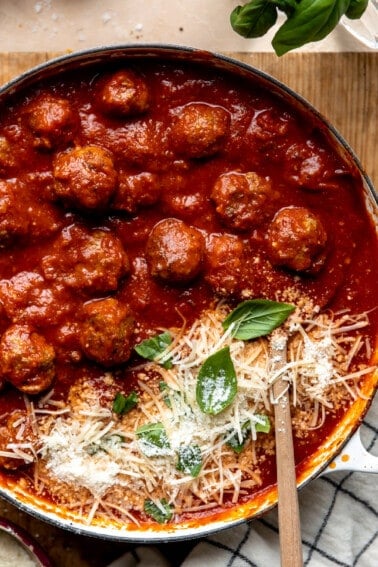 Easy homemade meatballs in a skillet with tomato sauce and topped with parmesan.