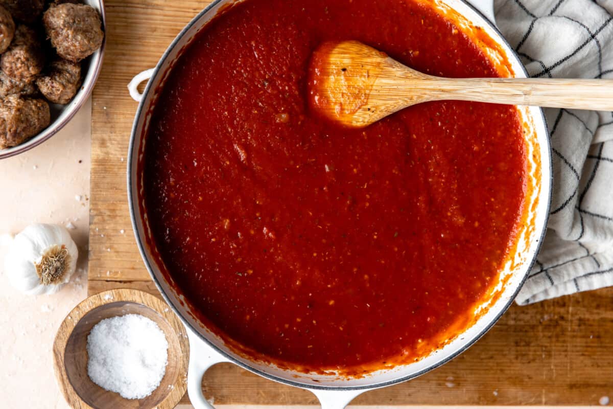 Marinara sauce cooking in a white skillet. 
